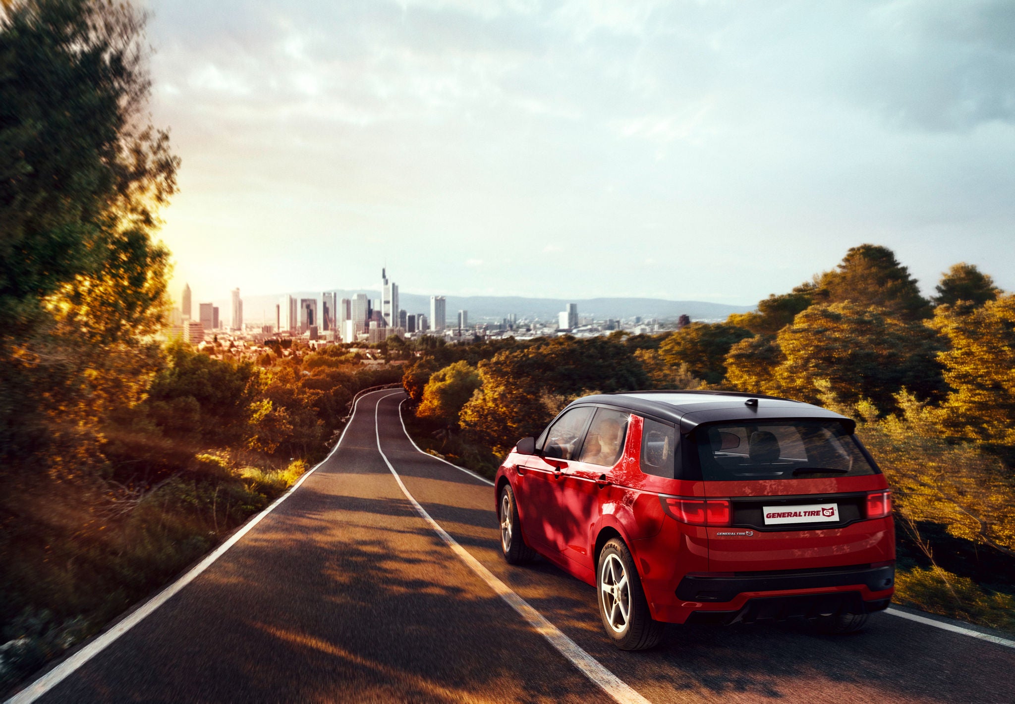 Red SUV driving towards a city